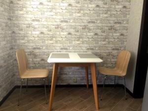a table and two chairs in front of a brick wall at Затишна квартира в центрі in Vinnytsya