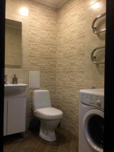 a bathroom with a toilet and a sink and a washing machine at Затишна квартира в центрі in Vinnytsya