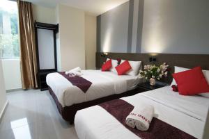 two beds in a hotel room with red and white pillows at Sun Inns Hotel Pasir Penambang (KS Botanic) in Kuala Selangor