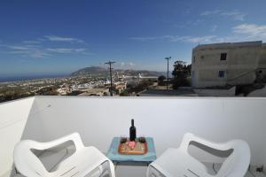 - deux chaises blanches et une table avec une bouteille de vin dans l'établissement King Thiras Hotel, à Fira