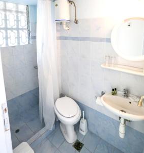 a white toilet sitting next to a sink in a bathroom at Hotel Karyatides in Agia Marina Aegina