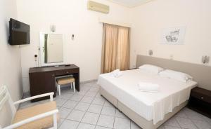 a bedroom with a bed and a desk and a mirror at Hotel Karyatides in Agia Marina Aegina