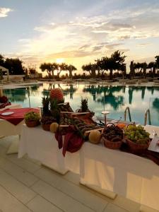a buffet of fruits and vegetables on a table in front of a pool at TUI BLUE Tropea in Santa Domenica
