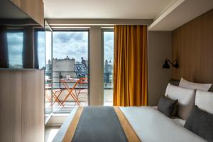 um quarto de hotel com uma cama e uma grande janela em Mercure Paris 17 Batignolles em Paris
