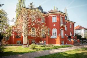 uma casa vermelha com uma árvore em frente em Villa am Park Apartment em Dresden