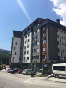 un gran edificio con coches estacionados en un estacionamiento en Стаи за гости Топ Старс Смолян, en Smolyan