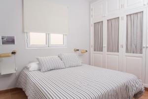 アリエタにあるModern home with Ocean Viewの白いベッドルーム(ストライプシーツ付きのベッド1台付)