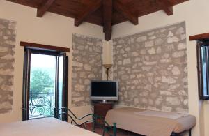 1 dormitorio con 2 camas y TV en la pared en Masseria Mastrangelo, en Prata Sannita