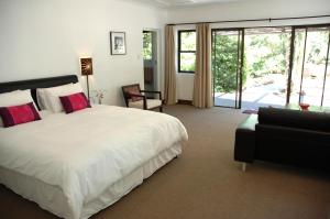- une chambre avec un grand lit blanc et un canapé dans l'établissement The Tarragon, à Hout Bay