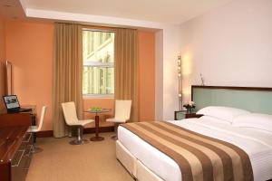 a hotel room with a bed and a desk and a window at Villa Rotana - Dubai in Dubai