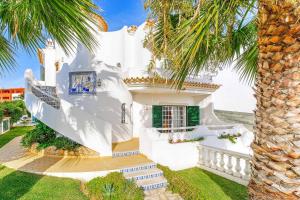 una casa blanca con una palmera delante de ella en Villa Torcato en Albufeira