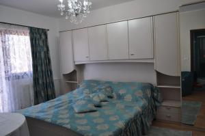 a bedroom with a bed with a blue blanket and white cabinets at Vila Teoharie in Ocnele Mari