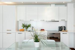 a kitchen with white cabinets and a glass table at Glasir Apartments Barcelona in Barcelona