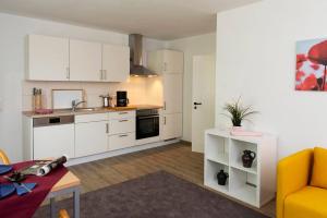 a kitchen with white cabinets and a yellow couch in a room at Parkblick Appartement - Entspannung pur! in Ober-Hambach