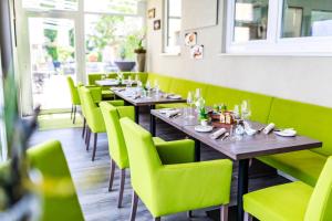 uma fila de mesas num restaurante com cadeiras verdes em Hotel Löwen em Eggenstein-Leopoldshafen