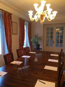 a dining room with a large wooden table and a chandelier at La villa rochette in Forges-les-Bains