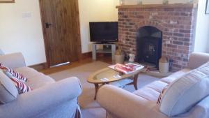 sala de estar con 2 sofás y chimenea en The Granary en Talgarth