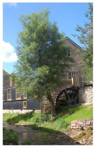 un árbol frente a una casa con un molino de agua en The Granary en Talgarth