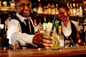 a man standing behind a bar holding a drink at Hotel Estheréa in Amsterdam