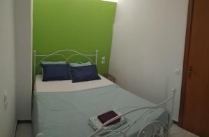 uma pequena cama com almofadas azuis e uma parede verde em "Apartment 2" em Lerápetra