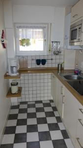 eine Küche mit schwarz-weiß kariertem Boden in der Unterkunft Ferienwohnung Dangast in Varel