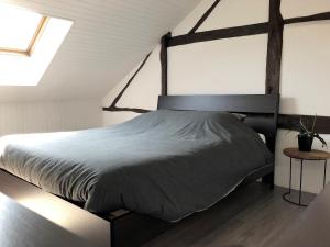 スタヴロにあるAu Petit Hのベッドルーム1室(大型ベッド1台、木製ヘッドボード付)