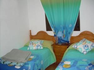 ロンダにあるVilla Robleのベッドルーム1室(ツインベッド2台、青いカーテン付)