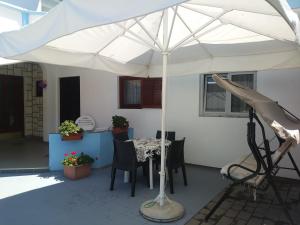 biały parasol na patio ze stołem i krzesłami w obiekcie Apartment Buba w mieście Tribunj