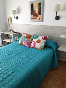 une chambre avec un lit avec des draps et des oreillers bleus dans l'établissement Hostal Argentina, à Cáceres