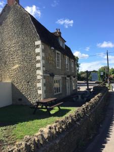 un bâtiment en pierre avec un banc devant lui dans l'établissement The Radnor Arms, à Malmesbury