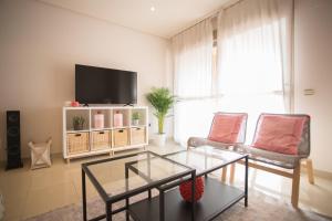 - un salon avec une télévision, 2 chaises et une table dans l'établissement Deluxe Playa Pacifico, à Malaga