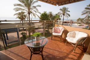 - un balcon avec une table et des chaises en verre et la plage dans l'établissement Deluxe Playa Pacifico, à Malaga