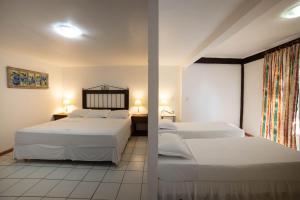 a bedroom with two beds and a window with two lamps at Pousada Casa do Catavento in Búzios