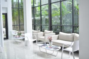 a living room with white furniture and large windows at Rezt Bangkok in Bangkok