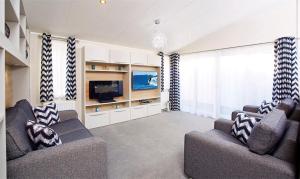 een woonkamer met 2 banken en een televisie bij New Forest Lodges Bashley Park in New Milton