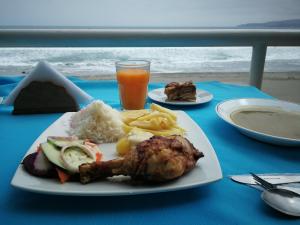 a table with a plate of food and a drink at Meflo Playa Grande in Chala