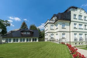 ein großes weißes Haus mit einem großen Hof in der Unterkunft Hotel Villa am Waldschlösschen in Dresden