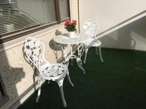 three chairs and a table with a flower pot on a balcony at City apartment in Rovaniemi