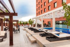 una vista exterior de un hotel con tumbonas y una piscina en Barcelo Guadalajara en Guadalajara