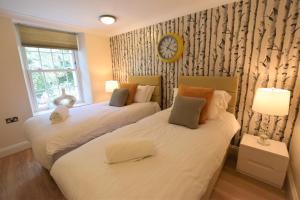 two beds in a room with a clock on the wall at Meridian Way - 3 Bed Apartment - Sleeps 7 in Bristol