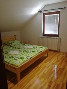 1 dormitorio con 1 cama con edredón verde y ventana en Apartman Đoković, en Višegrad