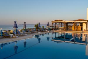 a swimming pool with chairs and a gazebo at Hotel Mimoza in Agia Marina Nea Kydonias