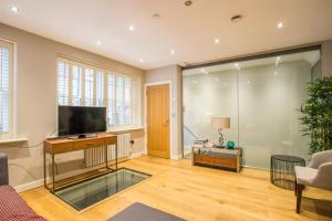 a living room with a flat screen tv and a couch at The Escalier Mews - Bright 3BDR Home in London