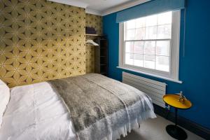 a bedroom with a bed with a yellow headboard and a window at Stylish Seaside Maisonette - 200m to Beach in Brighton & Hove