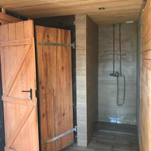 a bathroom with a shower with a wooden door at Domek letniskowy in Augustów