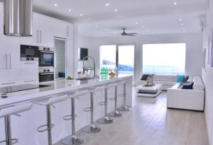 a white kitchen with a bar and a living room at Villa Mel II in Drasnice