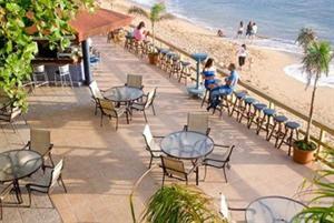 a beach area with tables, chairs and umbrellas at Villa Cofresi in Rincon