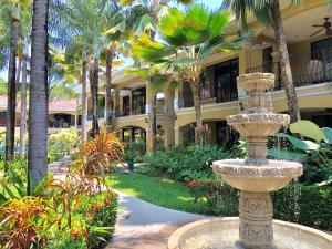 a large fountain in front of a building with palm trees at Monte Carlo Luxury Condominiums in Jacó +284 photos