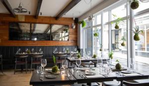 a dining room with tables and chairs and windows at The Black Bull Inn in Sedbergh