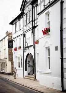a man walks down a street in front of white buildings at The Black Bull Inn in Sedbergh